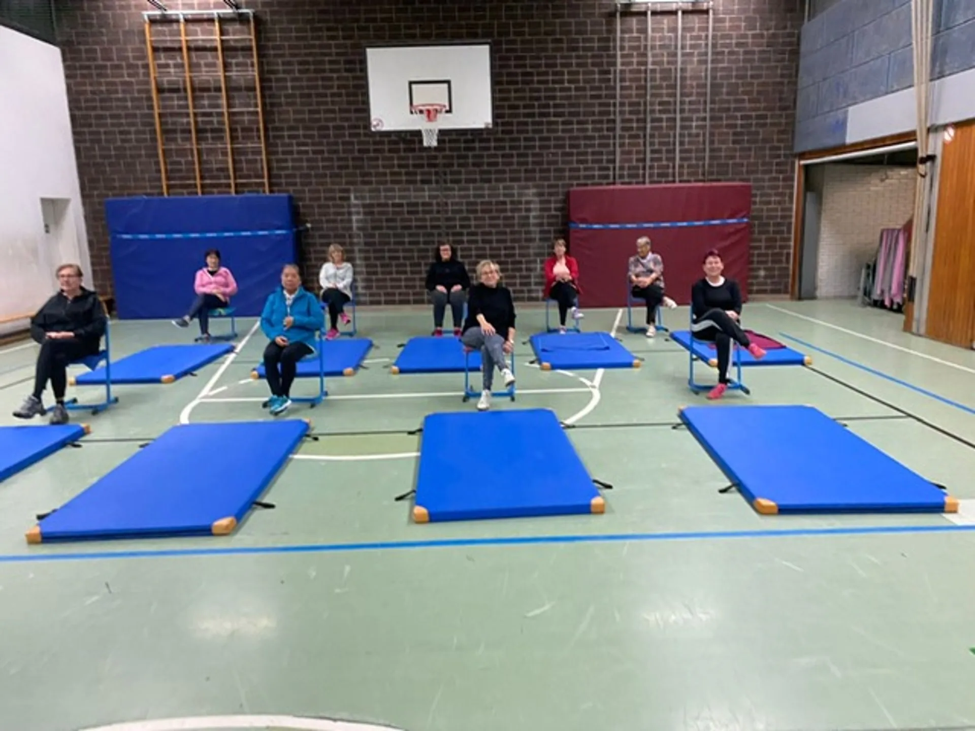 Teilnehmerinnen der Damengymnastik trainieren auf blauen Matten in der Turnhalle der ehemaligen Overbergschule