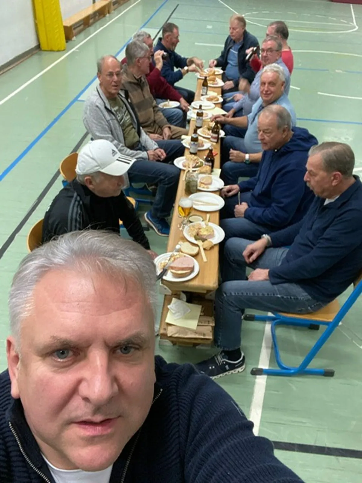 Mitglieder der Herrengymnastik beim gemeinsamen Essen in der Turnhalle